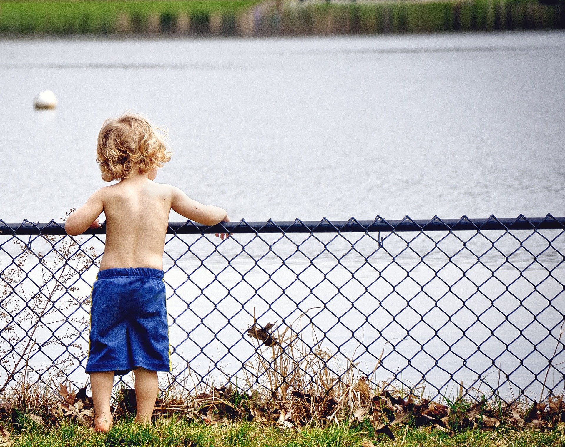 a kid standing at a fence by the lake representing how kids teach leadership